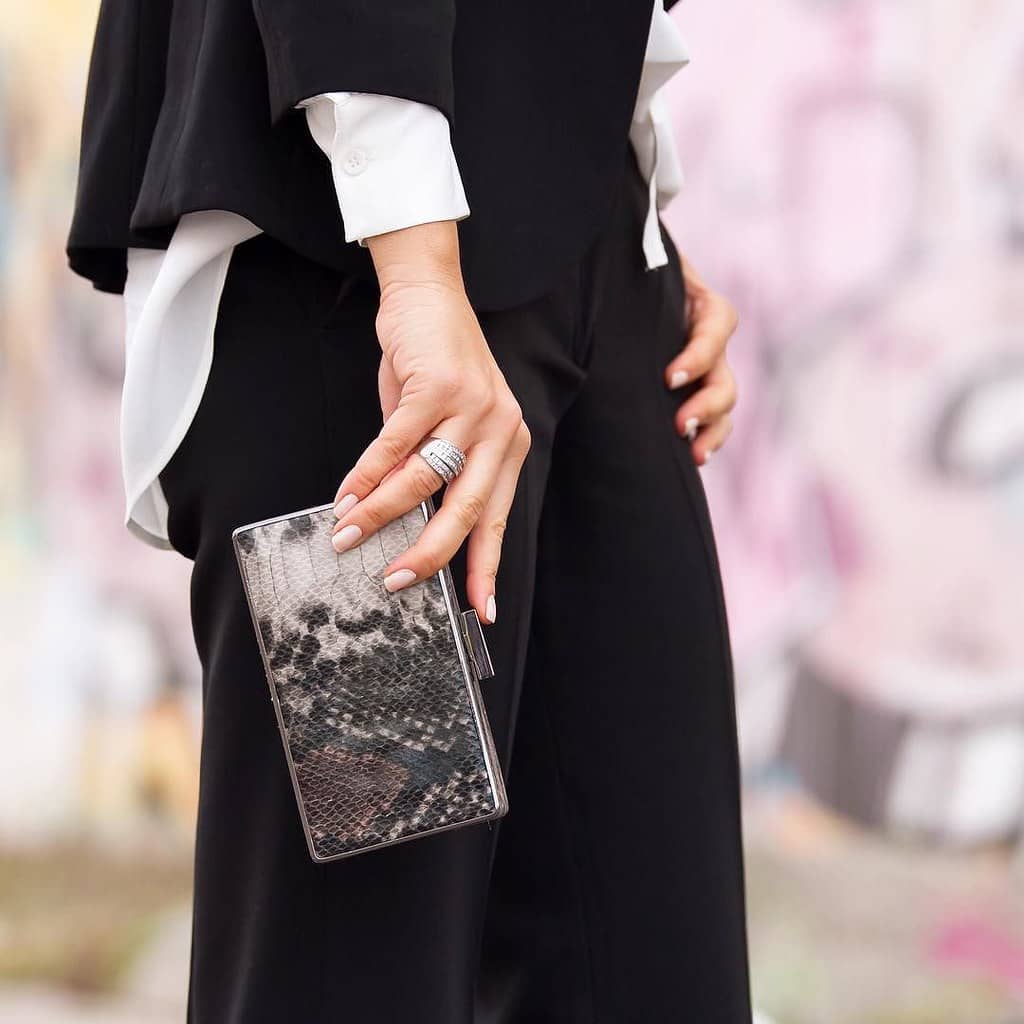 Stately woman holding black clutch in black wardrobe essentials