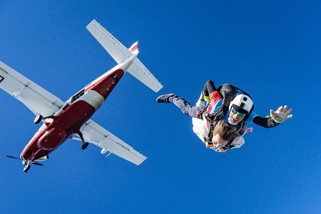 skydiving just below airplane in clear skies