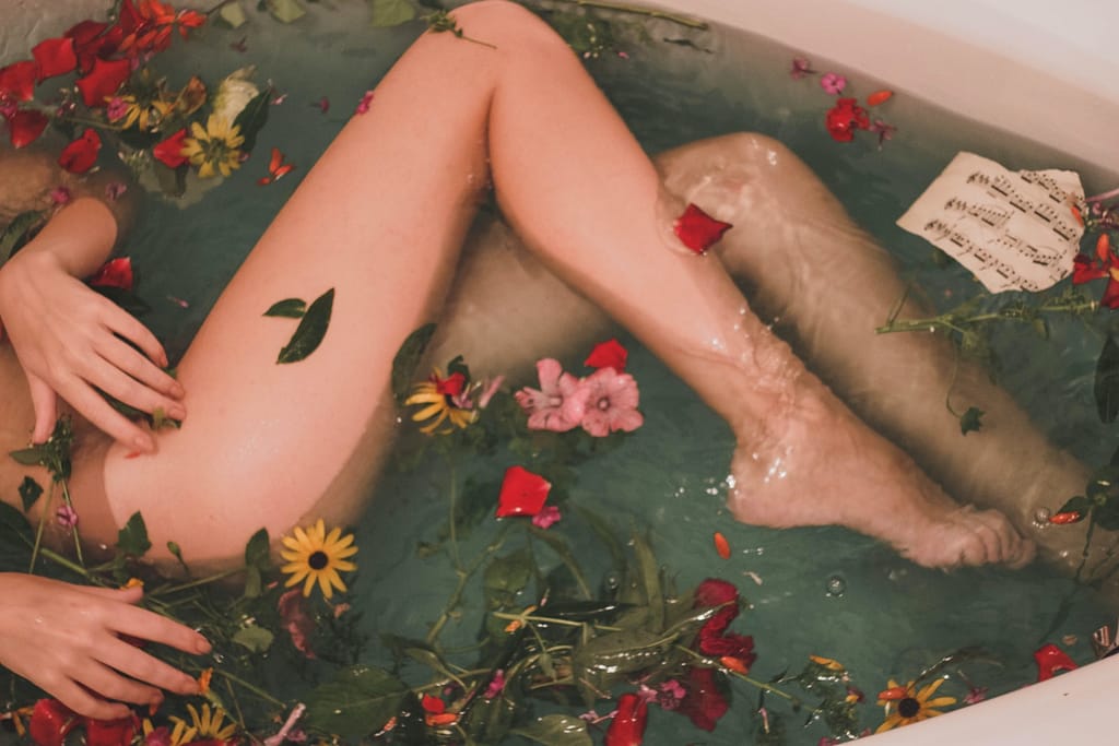 bathtub with water and flowers for smooth and moisturized skin
