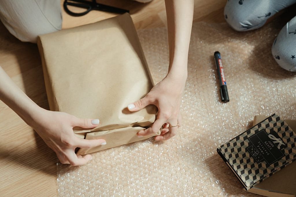 person using brown Kraft paper as sustainable product packaging