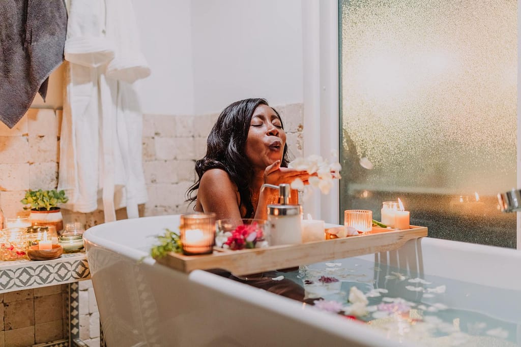 woman having a self care day at home in bathtub surrounded by candles