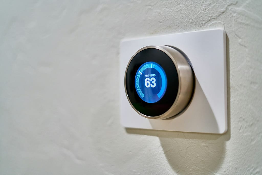 gray Nest smart thermostat displaying at 63 helping to conserve energy in the winter months