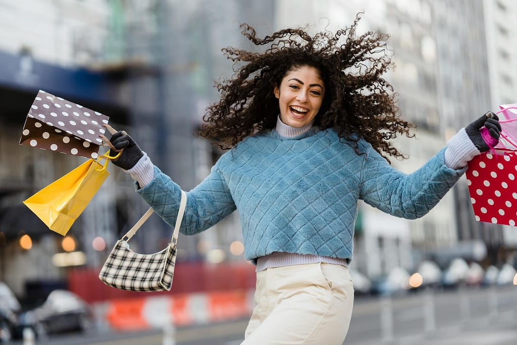 Happy woman jumping with shopping bags after making sustainable shopping decisions