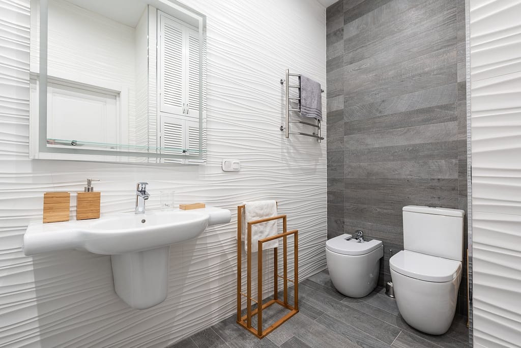 Contemporary bathroom interior with washbasin, toilet bowl, and a bidet displaying the environmental impact of bidet use.