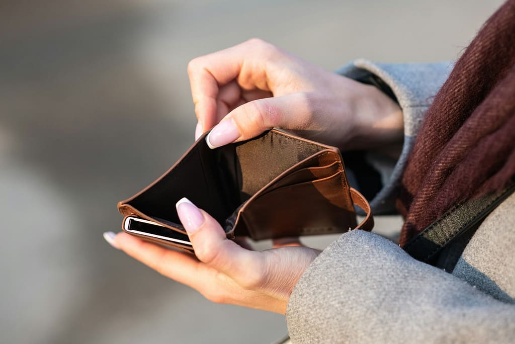 person holding empty brown wallet due to consumerism