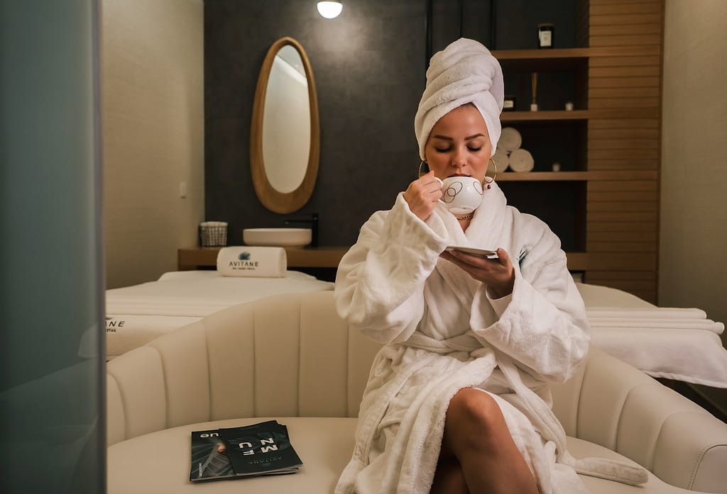 woman in white robe sitting on white couch enjoying her at home spa day