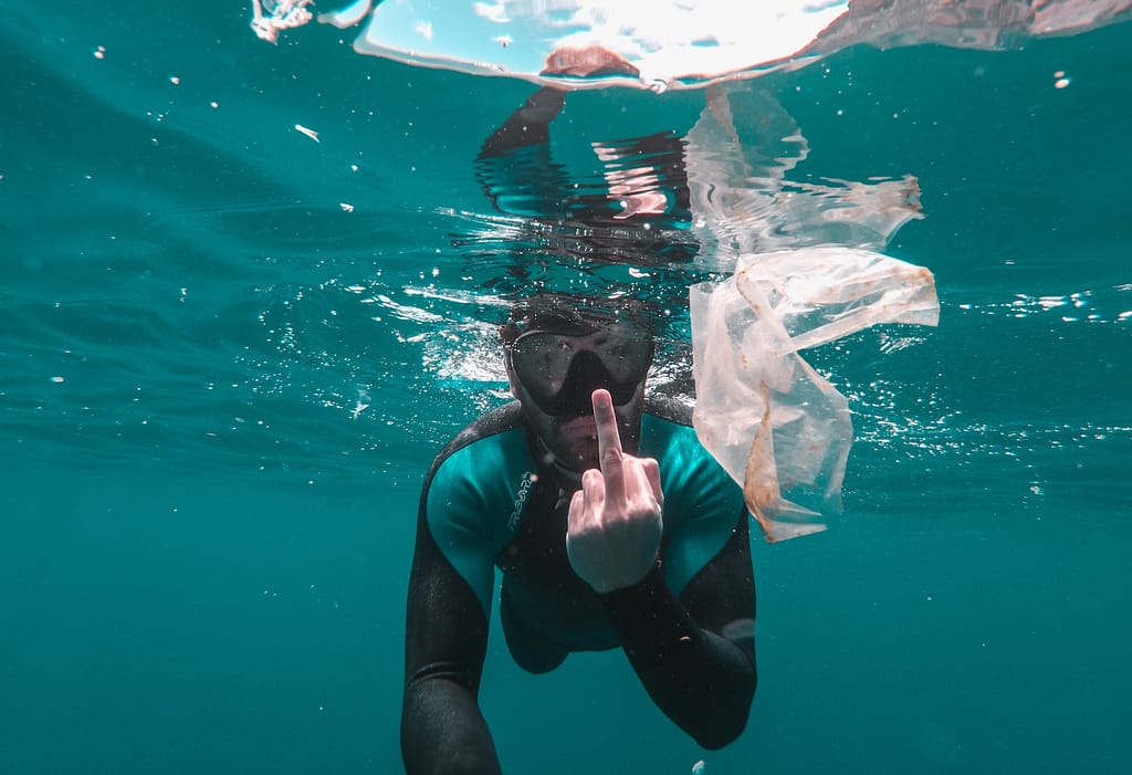 diver underwater photo flipping off the floating plastic