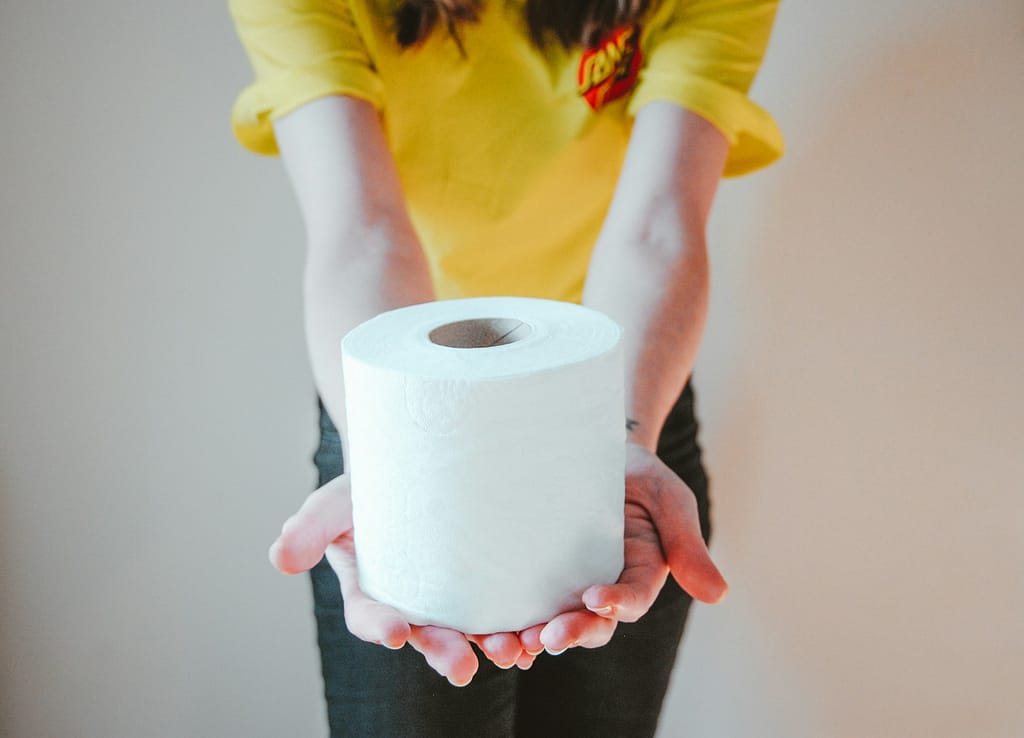 woman in yellow t-shirt holding white toilet paper in comparing the environmental impact of bidet use