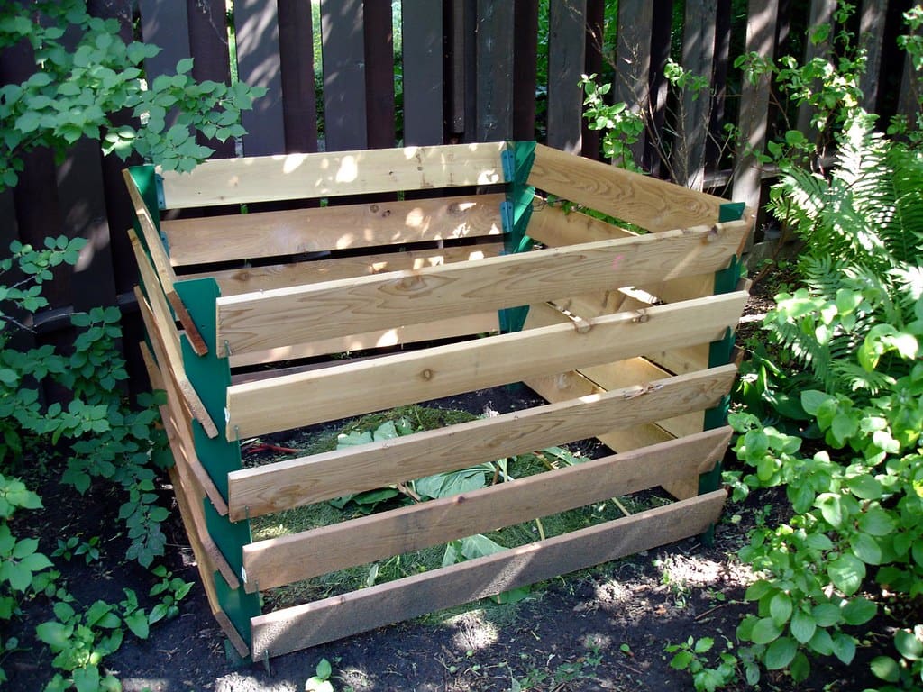 A wooden compost bin surrounded by trees