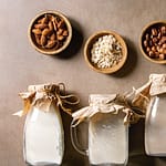 Various plant based milk alternatives with source ingredients in covered jars