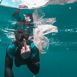 diver underwater photo flipping off the floating plastic