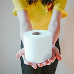 woman in yellow t-shirt holding white toilet paper in comparing the environmental impact of bidet use