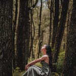 woman in grey dress sitting in nature pondering sustainable fashion questions