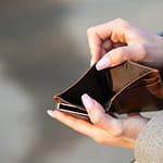 person holding empty brown wallet due to consumerism