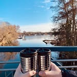 People holding reusable coffee Travel Mugs as a sustainable living choice overlooking a lake