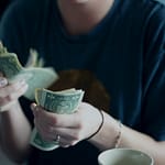 focus photography of person counting dollar banknotes while indulging in consumerism