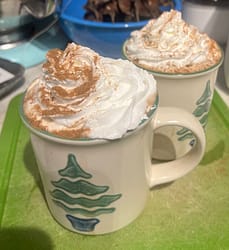 Vegan Hot Cocoa in Christmas mugs, topped with whipped cream and cinnamon