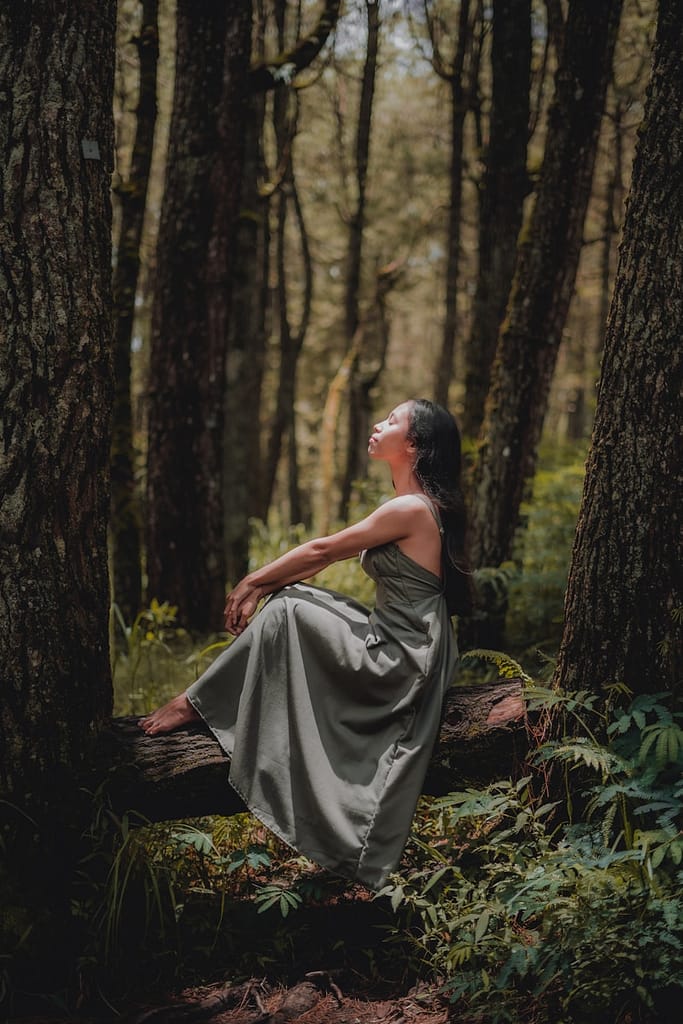 woman in grey dress sitting in nature pondering sustainable fashion questions