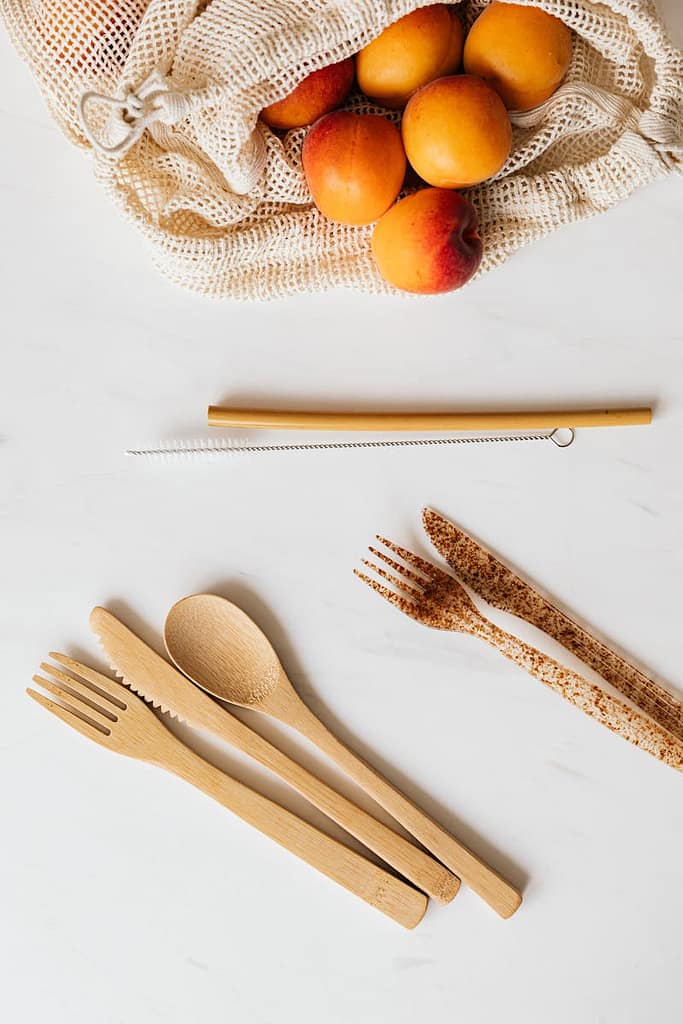 bamboo cutlery and mesh bag with oranges showing how easy building green habits at home is
