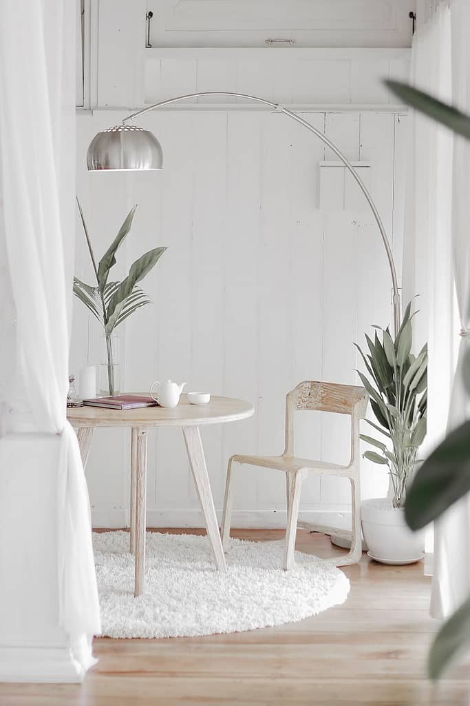 white steel chair in front round table on white rug in a decluttered and minimalist room