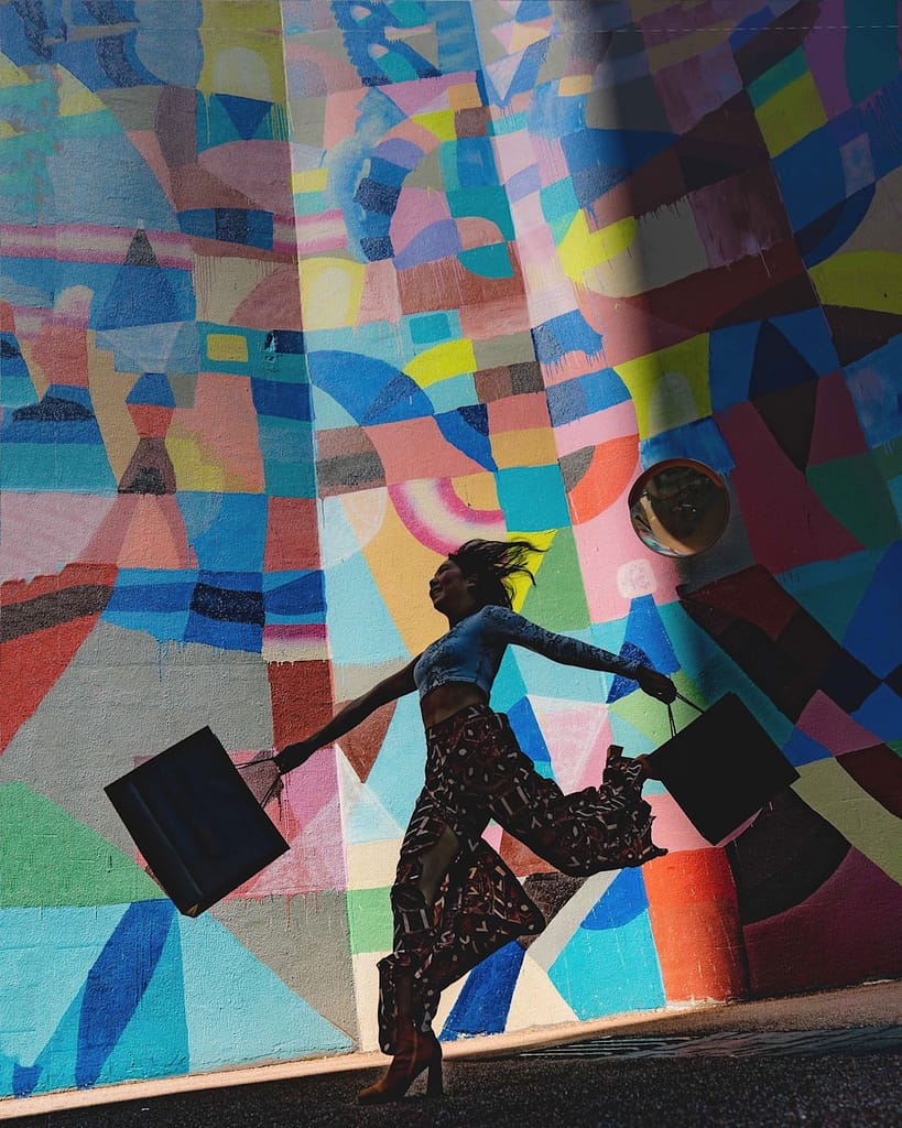 woman holding bag after shopping sustainably on a budget beside mural painting