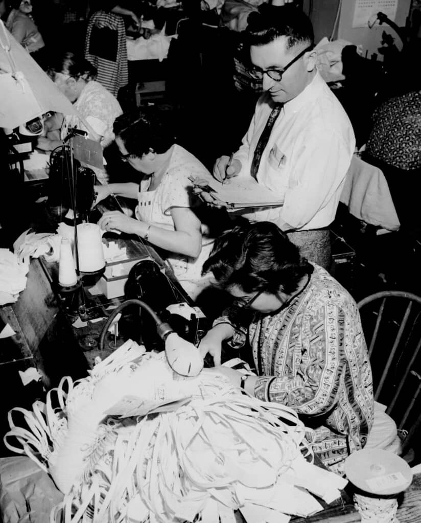 fashion garment worker surrounded by piles of clothes and manager